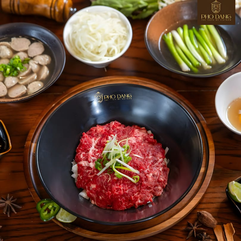 Pho Dang's raw beef, meatballs, and fresh ingredients for pho on a wooden table.