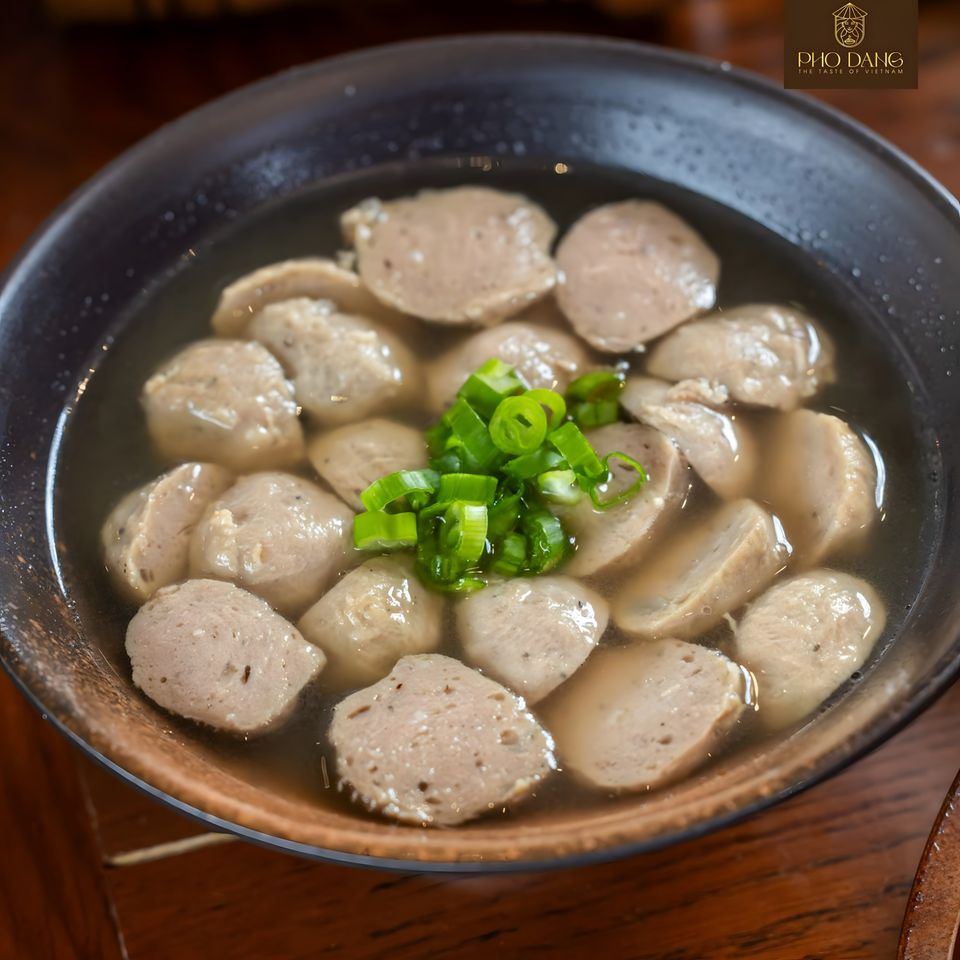 A close-up of a bowl of Pho Dang's Vietnamese meatball soup, garnished with chopped green onions.