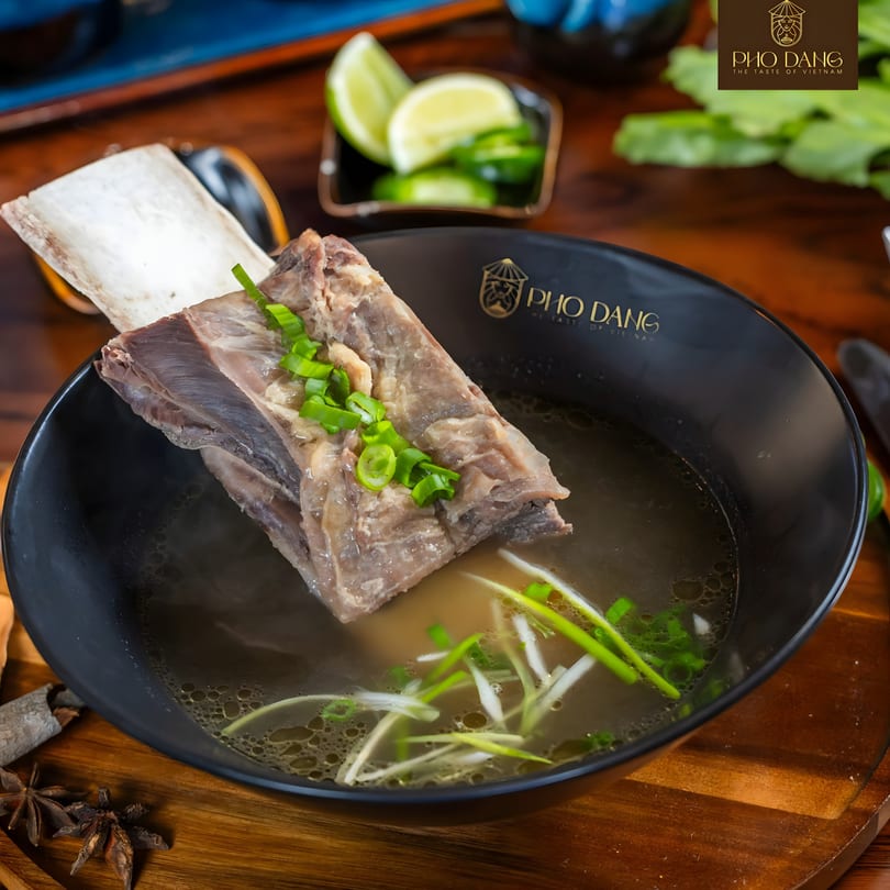 A large beef short rib in a bowl of Pho Dang pho, garnished with green onions.